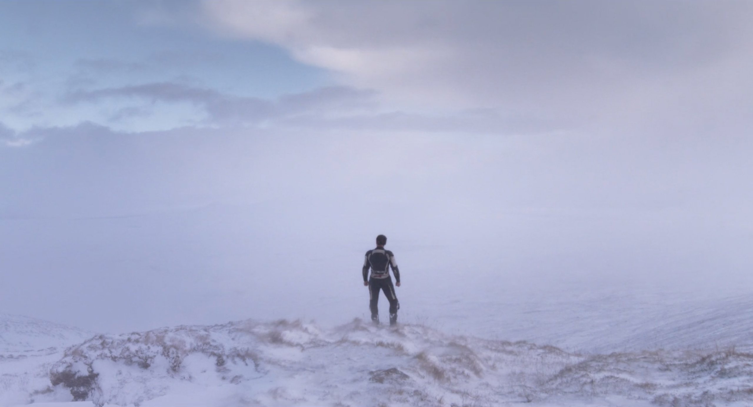 The Motorcycle Man looks over a snowy landscape while searching for The Woman in Under the Skin