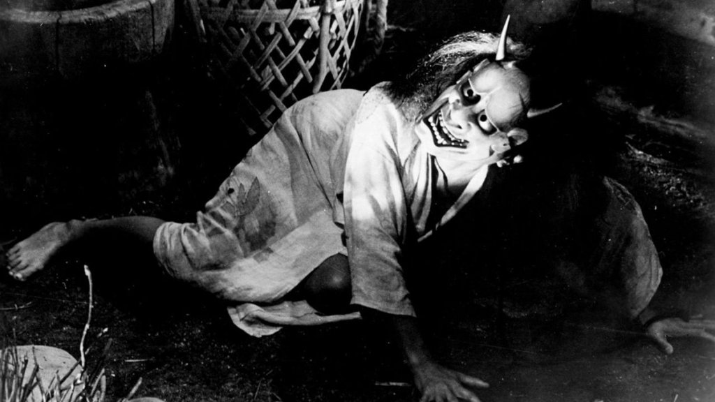 Kichi's mother lies on the floor and wears a dead samurai's mask in Onibaba (1965)