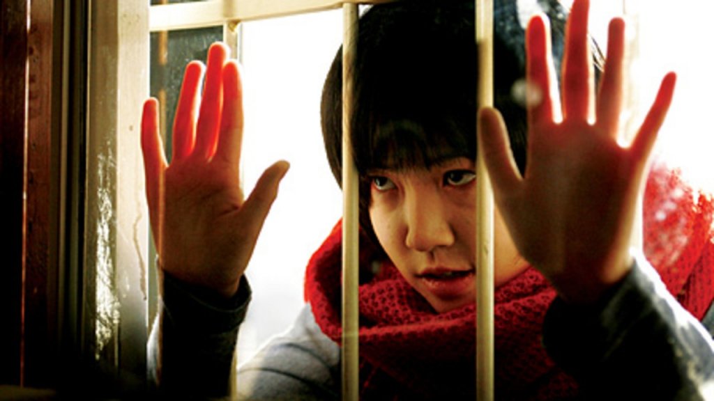So-jin (Shim Eun-kyung), possessed by a spirit, places her hands on a window in Possessed (2009)