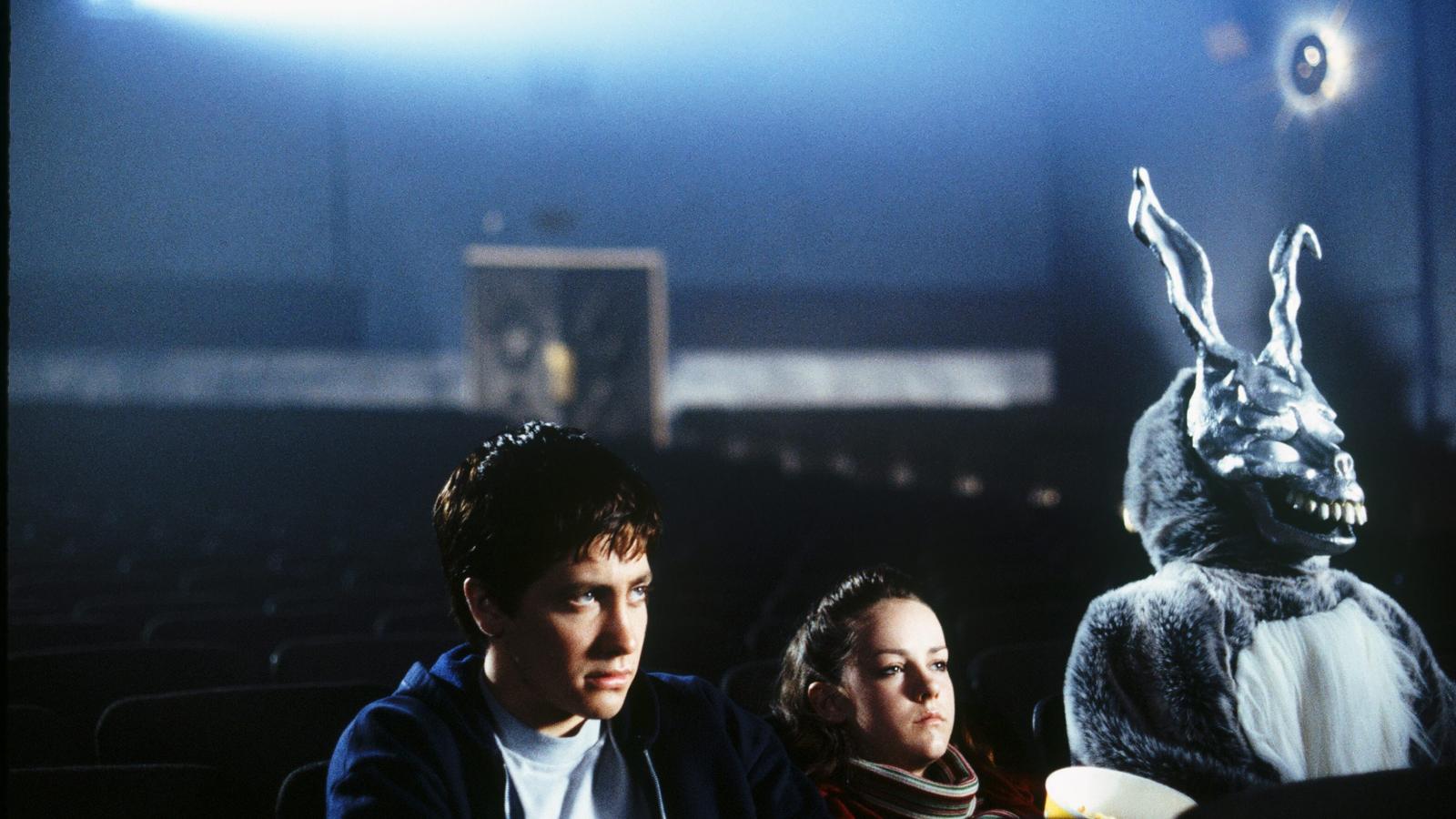 Donnie Darko (Jake Gyllenhaal) and Gretchen Ross (Jena Malone) sit in an empty theater with a demonic bunny