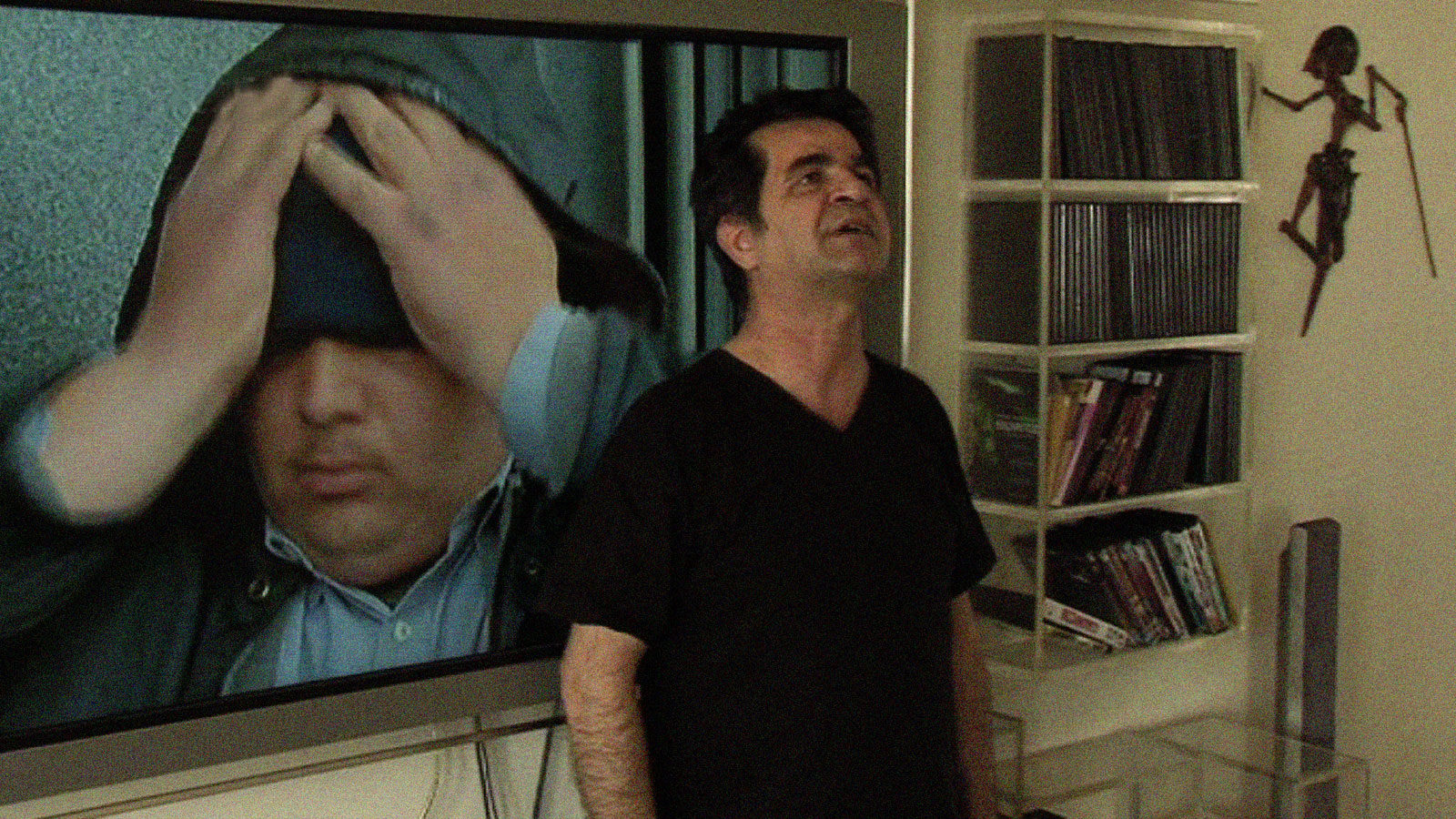 Jafar Panahi looks up as his film Crimson Gold plays in the background in This is Not a Film