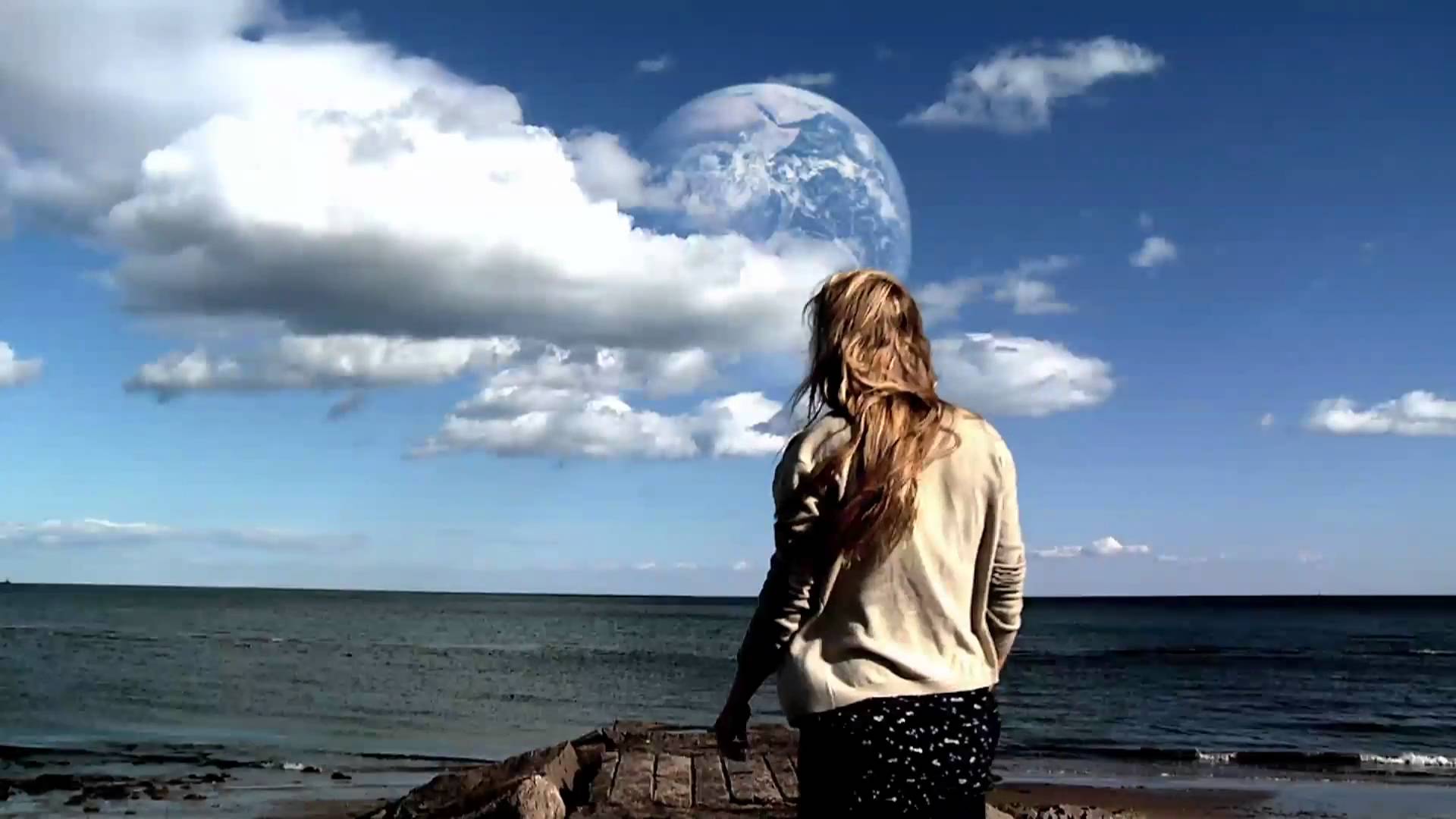 Rhoda Williams (Brit Marling) stands near water and stares at a second Earth that's been discovered in Another Earth