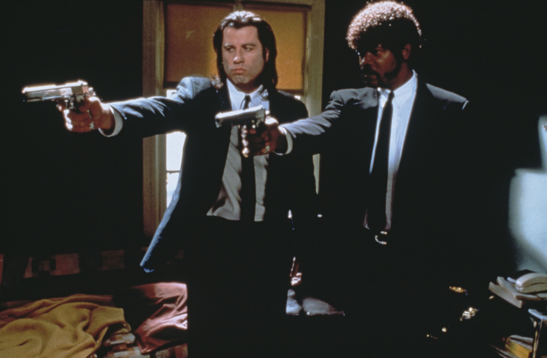 Vincent Vega (John Travolta) and Jules Winnfield (Samuel L. Jackson) point their guns at someone in Pulp Fiction