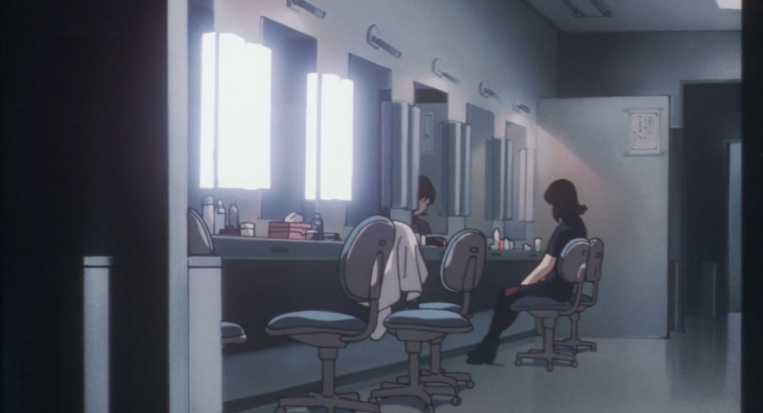 Mima sits in the dressing room dressed in black in a prayer position in Perfect Blue