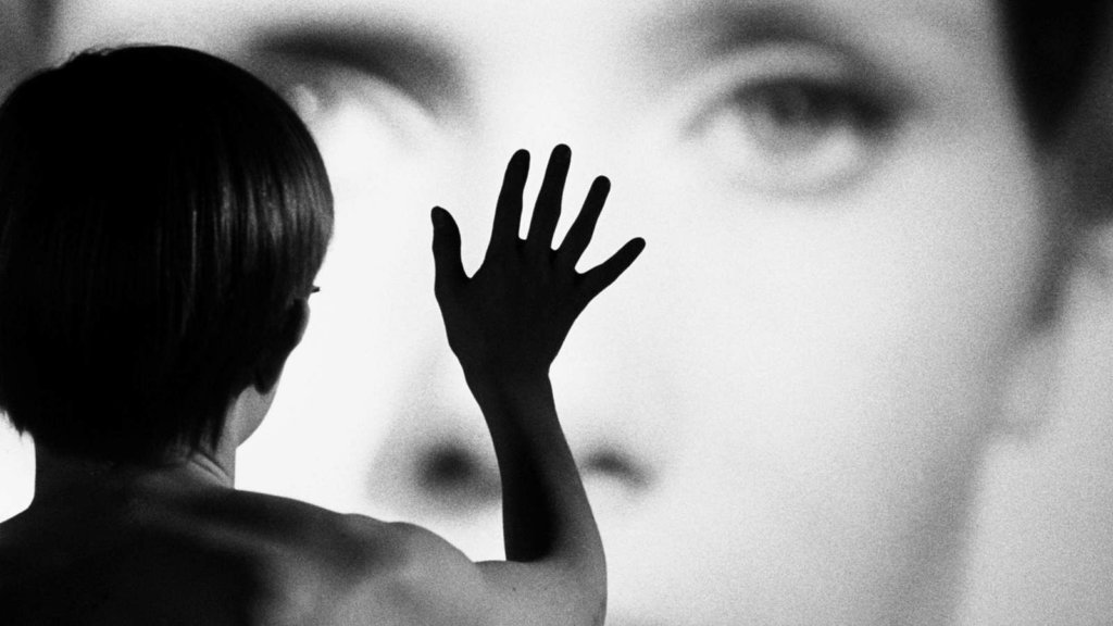 A young boy presses his hand against a giant photo of a woman in Persona