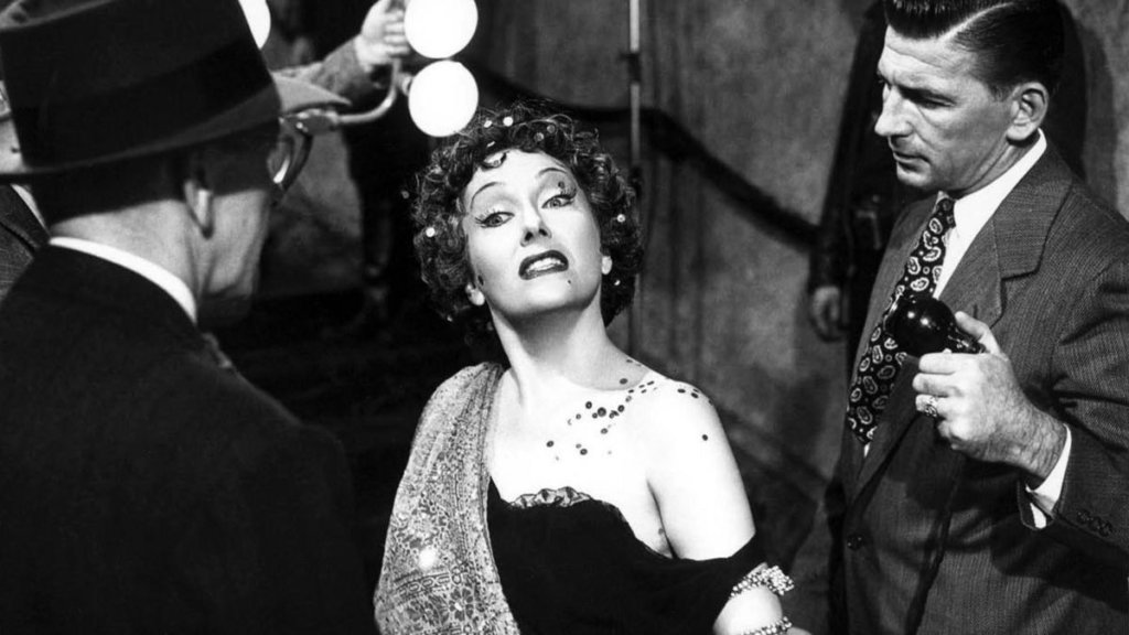 Norma Desmond has a crazy look in her eyes as she descends a staircase at the end of Sunset Boulevard