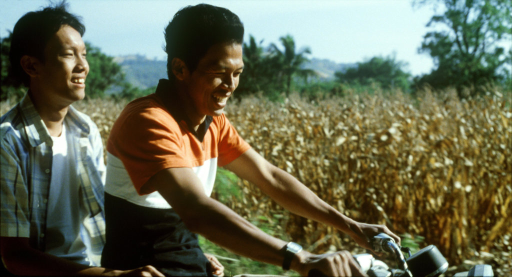 Keng and Tong smile as they ride a motorbike together in Tropical Malady