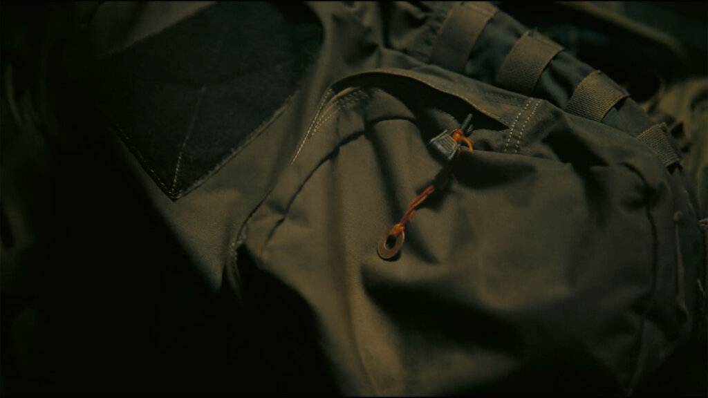A medallion hangs from Neil's backpack in Tenet
