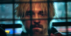 Connie (Robert Pattinson) sits in the back of a police car in Good Time