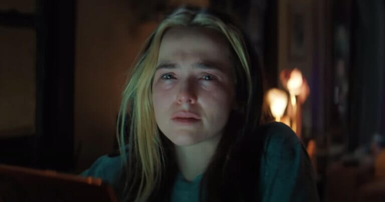 A woman with dark hair and blonde highlights looks sad as she stares into the camera