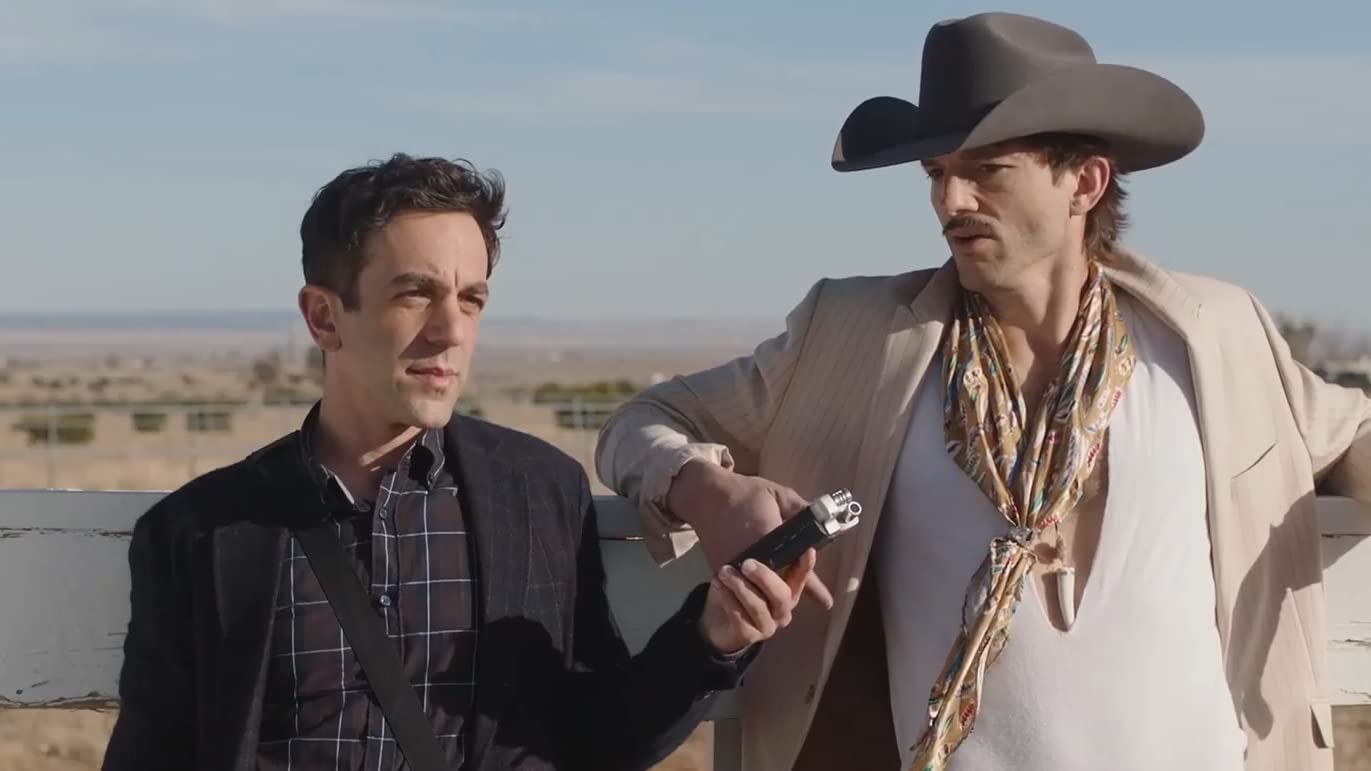 A man in a suit jacket records a man in a cowboy hat talking