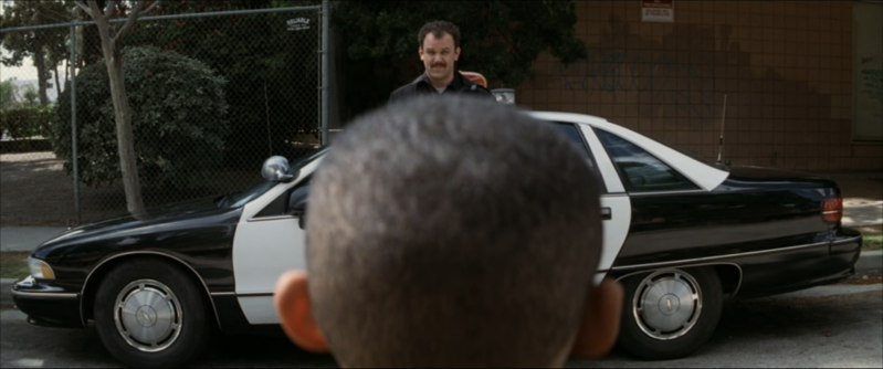 Jim looks at Dixon while standing next to his police car