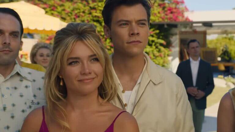 A woman and her husband stand outside looking at someone in front of them