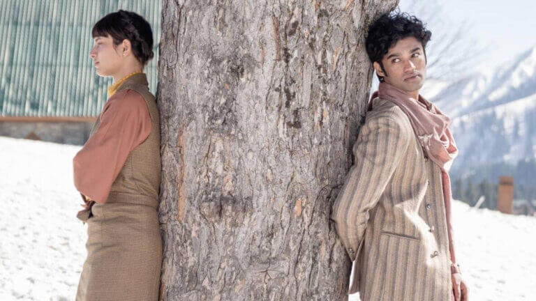 A woman stands on the left side of a tree while a man stands on the right side