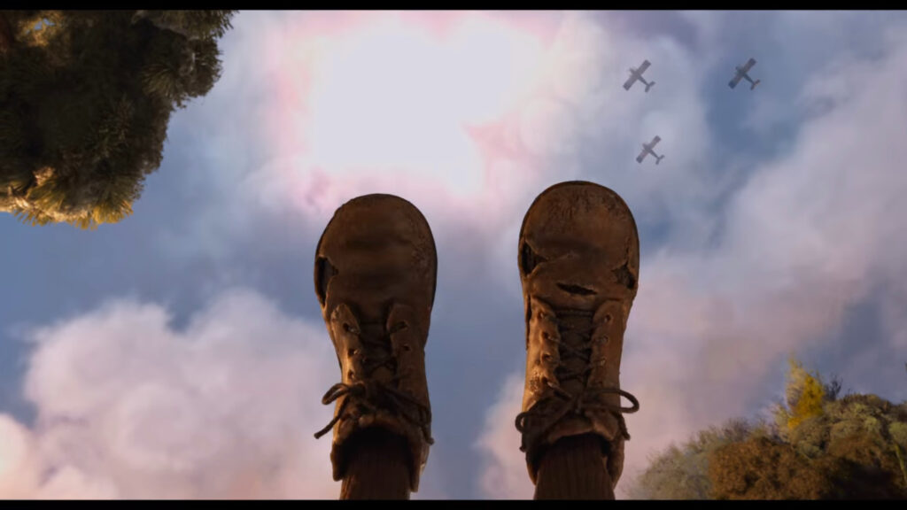 A POV shot of someone on a swing, their feet kicking high into the air, but in the sky above three military planes fly overhead. 
