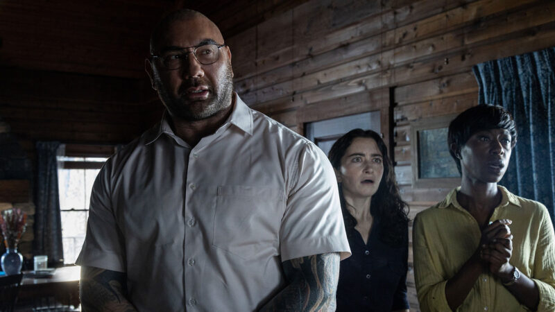 A man and two women stare at something in horror in a cabin