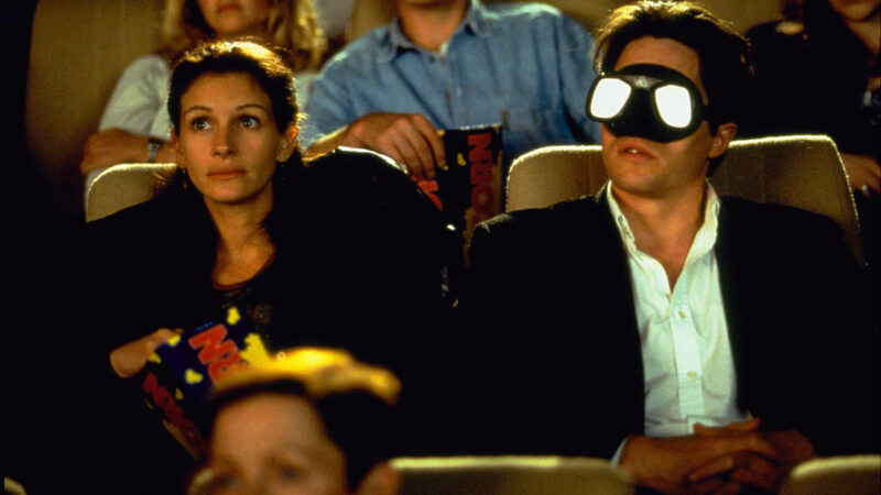 A woman sits next to a man wearing scuba goggles in a movie theater