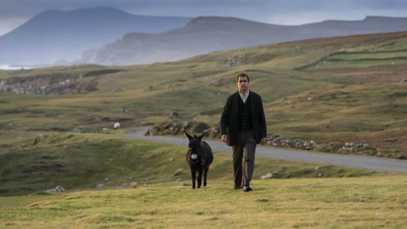 A man walks with a donkey in the hills of Ireland