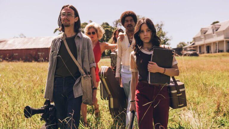 A film crew walks through a field