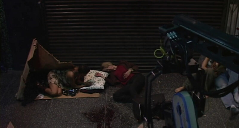 Several homeless people lay on the sidewalk as a camera films