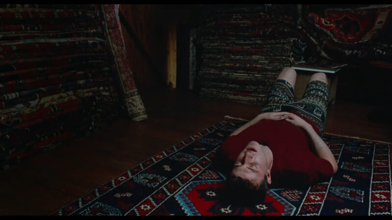 A man lies on a rug