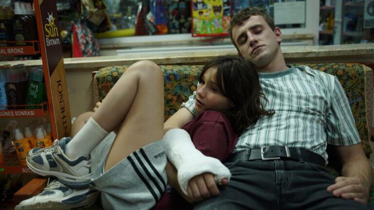 Calum wraps his casted arm around his daughter Sophie while sitting on a couch