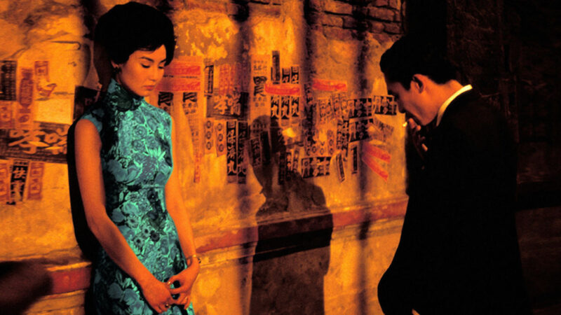 A woman and a man stand in an alleyway, with the man's shadow hitting the wall