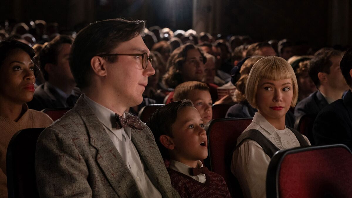 A boy sits with his parents in a movie theater