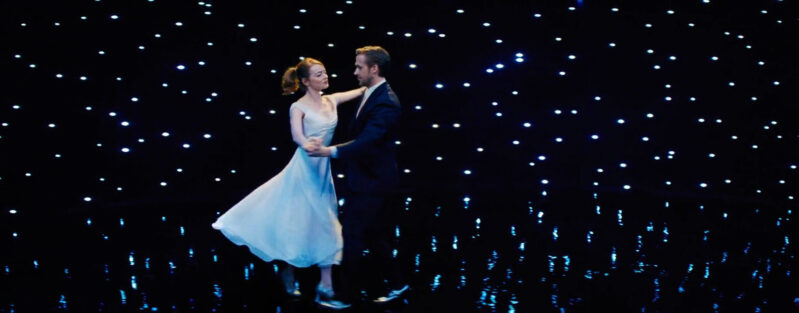 A woman and a man dance in a room sprinkled with lights