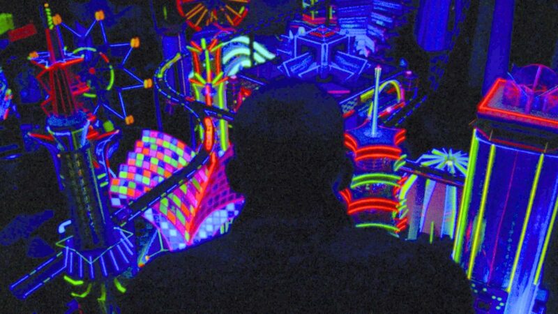 A man looks at a model city made of neon lights