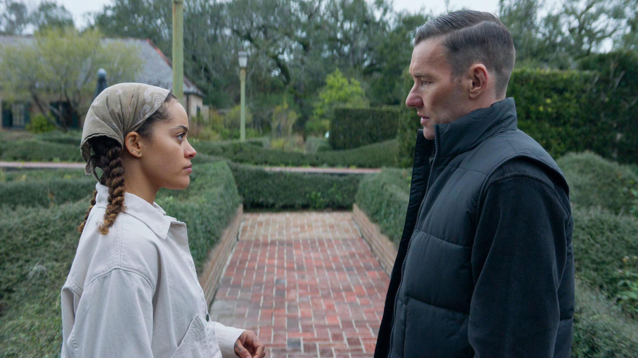 A woman and a man stare at each other while standing in a plant nursery