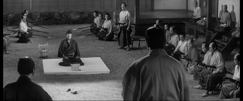 A samurai sits in a courtyard with other samurais