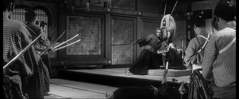 A samurai raises his sword to several incoming samurai while clutching ancient samurai armor