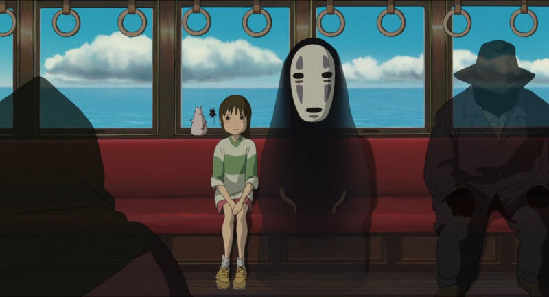 A little girl and a masked creature sit together on a train