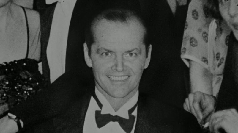 A man smiles in a black and white photograph
