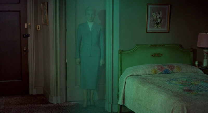 A woman is shrouded in a green haze in a room