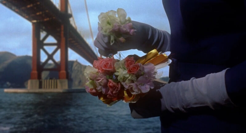 A woman pulls flowers from a bouquet in front of the Golden Gate Bridge