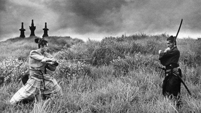Two samurai holding swords stand off in a meadow