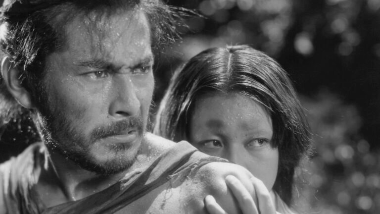 A sweaty man stares intensely as a woman peeks over his shoulder