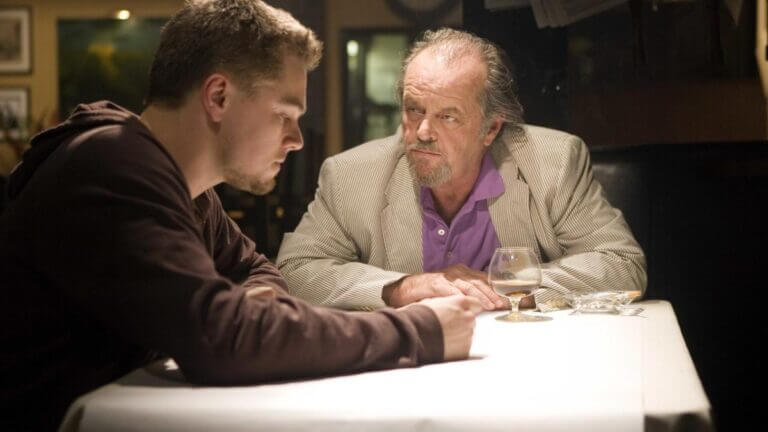 A younger man sits and contemplates as an older man stares at him