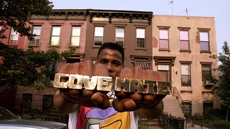 A man wears jewelry on his hands that read "love" and "hate"