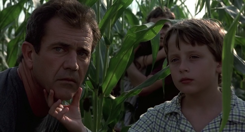 Morgan turns Graham's face to look at something in a field of crops