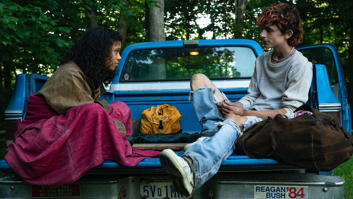 Lee and Maren sit on the back of a truck looking at each other