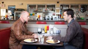 Old Joe sits across from Young Joe at a diner
