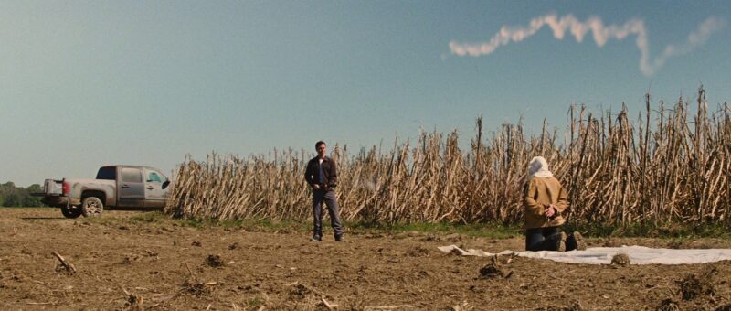 Young Joe stands ready to shoot a hooded man with his blunderbuss in a cornfield
