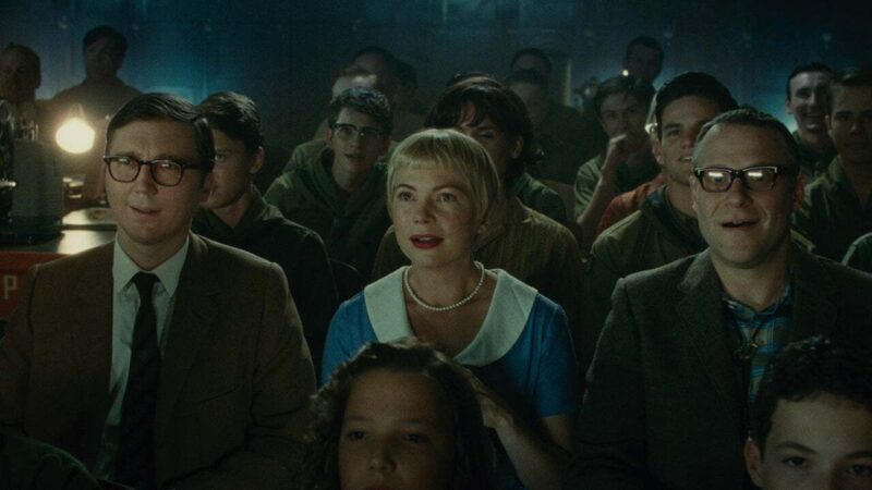 Burt, Mitzi, and Bennie sit in a crowded room as a projector plays a movie from behind