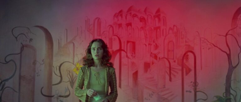 Suzy stands in fear in a room with a red light on the wall