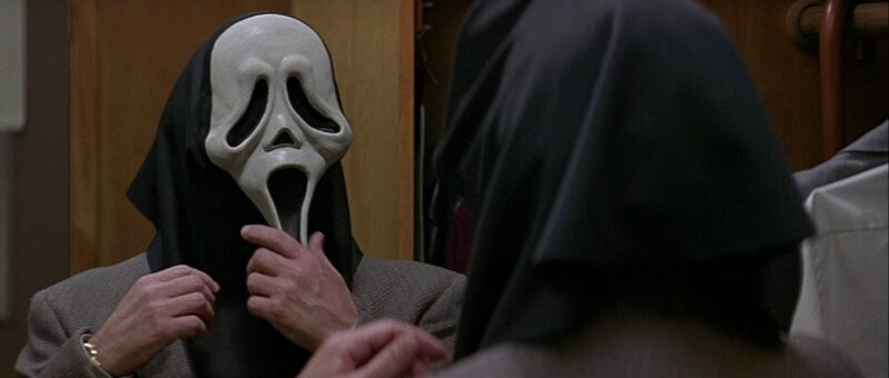 Principal Himbry puts on the Ghostface mask in the mirror of his office