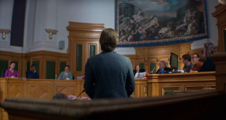 A woman stands in a French courtroom, facing the judges.