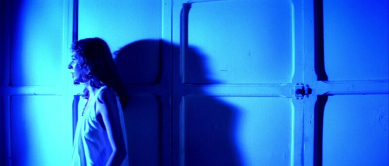 Sara flees in terror in a blue room away from a maleficent force